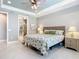 Bedroom showcasing the tiled floors, decorative headboard, ceiling fan, and a glimpse into the adjacent bathroom at 13724 Quinta St, Venice, FL 34293