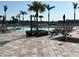 Community pool with tropical palm trees and lounge chairs surrounding the area on a sunny day at 13724 Quinta St, Venice, FL 34293