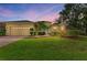 Charming home with a two-car garage, lush landscaping, and a welcoming entrance, enhanced by the colorful sunset backdrop at 14239 Nighthawk Ter, Lakewood Ranch, FL 34202