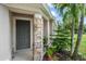 Close-up of front door featuring stone pillar, green plants, and lush tropical landscaping at 15032 Skip Jack Loop, Lakewood Ranch, FL 34202