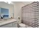 Bright bathroom features a single sink vanity, granite countertop, toilet and shower with patterned curtain at 15719 Barefoot Beach Dr, Lakewood Ranch, FL 34211