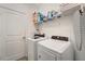 Bright laundry room features a modern washer and dryer, shelf and a door at 15719 Barefoot Beach Dr, Lakewood Ranch, FL 34211