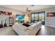 Bright living room with large sectional sofa, ceiling fan, and sliding glass doors to the lanai at 15719 Barefoot Beach Dr, Lakewood Ranch, FL 34211