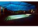 An evening view of an illuminated, screened pool and spa with backyard lake views at 15719 Barefoot Beach Dr, Lakewood Ranch, FL 34211