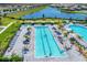 Stunning aerial view of the community pool area, featuring ample seating, lush palm trees, and sparkling swimming pools at 15719 Barefoot Beach Dr, Lakewood Ranch, FL 34211