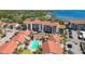 Scenic aerial view of the condos with red tile roofs, parking, palm trees, and a community pool at 1624 Stickney Point Rd # 24-206, Sarasota, FL 34231