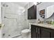 Bathroom featuring tiled shower, dark vanity with granite countertop and round mirror at 1624 Stickney Point Rd # 24-206, Sarasota, FL 34231