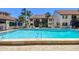 Community pool with a clear blue swimming area surrounded by lounge chairs and palm trees on a bright, sunny day at 1624 Stickney Point Rd # 24-206, Sarasota, FL 34231