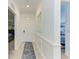 Hallway with white walls, white trim, mirror, white door, and view into rooms with tile floor and small rug at 18114 Gawthrop Dr # 306, Bradenton, FL 34211
