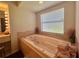 Bathroom featuring a bright Hollywood-style vanity and large soaking tub next to a sunlit window at 18513 Placid Ave, Port Charlotte, FL 33948