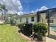 Well-manicured lawn features tropical landscaping near screened-in lanai and pool at 18513 Placid Ave, Port Charlotte, FL 33948