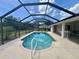 Enclosed pool area with screened-in patio, blue skies, and lush landscaping at 18513 Placid Ave, Port Charlotte, FL 33948