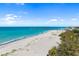 Expansive beach view with white sand and clear blue ocean water extending to the pier under a partly cloudy sky at 2929 Siesta Dr, Venice, FL 34293