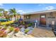 Beautiful front yard features a wooden walkway, colorful flowers, tropical plants and a cozy bench by the front door at 2929 Siesta Dr, Venice, FL 34293