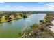 Wide aerial shot showcasing a large pond surrounded by green landscape with palm trees and clear blue sky above at 2929 Siesta Dr, Venice, FL 34293