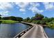 Scenic golf course view featuring a wooden bridge over water, lush greenery, and blue skies with fluffy clouds at 340 Osprey Point Dr, Osprey, FL 34229