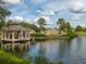 Scenic view of The Venice Golf and Country Club entrance sign with lake and gazebo in a lush, tropical setting at 355 Melrose Ct, Venice, FL 34292