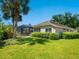 Exterior view of the home showing the screened-in lanai, lush landscaping, and well-maintained lawn at 355 Melrose Ct, Venice, FL 34292