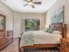 Bright primary suite features a ceiling fan, ensuite bath, and sliding glass doors to a screened patio and pool at 355 Melrose Ct, Venice, FL 34292