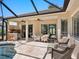 An inviting outdoor space with covered patio, summer kitchen, dining table, and seating area adjacent to the pool at 355 Melrose Ct, Venice, FL 34292