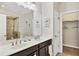 Bathroom featuring a double sink vanity with dark cabinets, white countertops, a linen closet, and a glass shower at 4236 Expedition Way # 106, Osprey, FL 34229