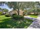 Home exterior with a clay tile roof, a well-manicured lawn, mature trees, and beautiful landscaping at 4713 Sweetmeadow Cir, Sarasota, FL 34238