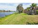 A large grassy backyard leads to a serene lake view and screened lanai at 4961 Sabal Lake Cir, Sarasota, FL 34238