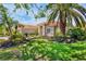 Quaint single-story home with a red tile roof, surrounded by lush landscaping, showcasing its curb appeal at 4961 Sabal Lake Cir, Sarasota, FL 34238