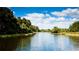 Serene lake surrounded by lush green trees and a clear blue sky with fluffy white clouds at 4961 Sabal Lake Cir, Sarasota, FL 34238