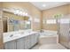 Bright bathroom with double sink vanity, soaking tub, and glass enclosed shower at 4961 Sabal Lake Cir, Sarasota, FL 34238