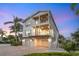 Beautiful two-story beach house with white siding, double balconies, and a two-car garage at dusk at 497 Island Cir, Sarasota, FL 34242