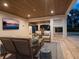 Stylish outdoor living area with a television, wood plank ceiling, comfortable seating, and travertine tile flooring at 497 Island Cir, Sarasota, FL 34242