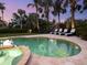Beautiful backyard with a heated pool and jacuzzi with a spa, surrounded by palm trees, and elegant landscaping at 497 Island Cir, Sarasota, FL 34242