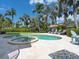 A luxurious pool and jacuzzi are surrounded by palm trees, lounge chairs, and beach umbrellas at 497 Island Cir, Sarasota, FL 34242