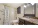 Bathroom featuring a vanity with granite countertop, a framed mirror, and a tub with shower and patterned curtain at 500 N Jefferson Ave # 5, Sarasota, FL 34237
