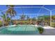 Sparkling screened-in pool surrounded by lush tropical landscaping, complete with an umbrella-covered table and chairs at 5022 46Th W St, Bradenton, FL 34210