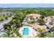 An aerial view showcases the community pool, palm trees, and surrounding properties near a lake at 5405 46Th W Ct, Bradenton, FL 34210
