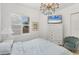 Bright bedroom featuring a TV, plantation shutters, a chandelier, and a comfortable bed at 5405 46Th W Ct, Bradenton, FL 34210