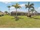Manicured backyard with lush green grass, tropical palm trees, and an inviting screened-in lanai at 5480 White Ibis Dr, North Port, FL 34287