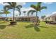 Lush backyard featuring a well-maintained lawn, tropical palm trees, and a charming screened-in lanai at 5480 White Ibis Dr, North Port, FL 34287