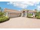 Charming single-story home featuring a tile roof, brick driveway, and well-manicured landscaping at 5480 White Ibis Dr, North Port, FL 34287