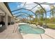 Inviting screened-in pool area with travertine decking, landscaping, and a clear view of the surrounding greenery at 5480 White Ibis Dr, North Port, FL 34287