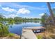 Tranquil lake view from a wooden dock, surrounded by lush greenery and reflective water at 5623 Palm Aire Dr, Sarasota, FL 34243