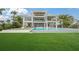 A backyard view of a stunning three-story home with a pristine pool and perfectly manicured lawn at 619 Key Royale Dr, Holmes Beach, FL 34217