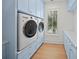 Charming laundry room with blue cabinetry, a front load washer/dryer, and a window with natural light at 619 Key Royale Dr, Holmes Beach, FL 34217