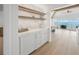 This wet bar features floating shelves with lighting, a beverage fridge, and views of the water at 619 Key Royale Dr, Holmes Beach, FL 34217