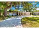 Charming single-story home with mature trees, neutral tones, front yard landscaping, and a long concrete driveway at 7158 S Leewynn Dr, Sarasota, FL 34240
