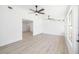 Bright, white living room with light wood floors featuring two ceiling fans and a view into the next room at 7158 S Leewynn Dr, Sarasota, FL 34240