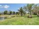 Serene backyard with lush lawn, palm trees, and tranquil water view, creating a private oasis at 7319 Westminster Ct, University Park, FL 34201