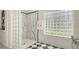 Modern bathroom featuring glass block wall, marble shower, black accents and checkered tile floor at 7319 Westminster Ct, University Park, FL 34201